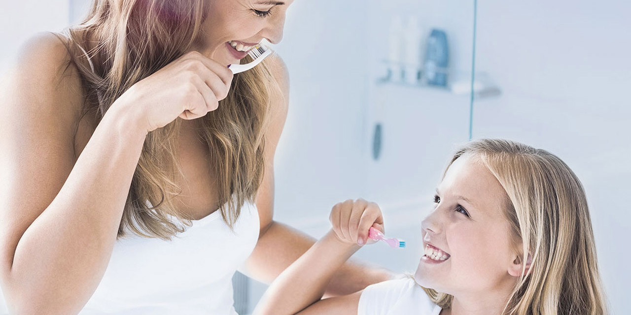 Mother and daugther brushing their teeth
